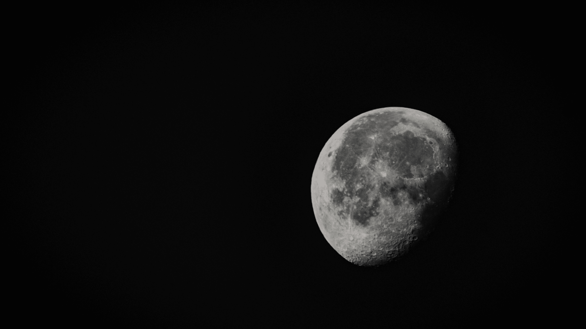 A bright, detailed view of a waxing gibbous moon against a dark black sky, highlighting its craters and surface texture