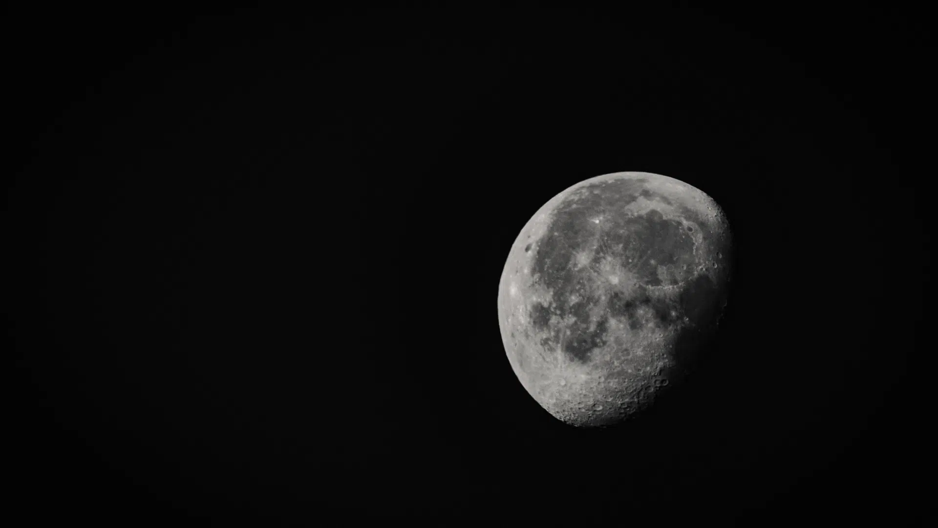A bright, detailed view of a waxing gibbous moon against a dark black sky, highlighting its craters and surface texture