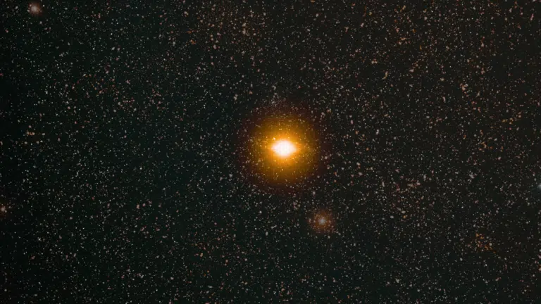 _A bright, luminous star that seems like sun dominates a dark expanse of the night sky densely filled with countless smaller white stars.