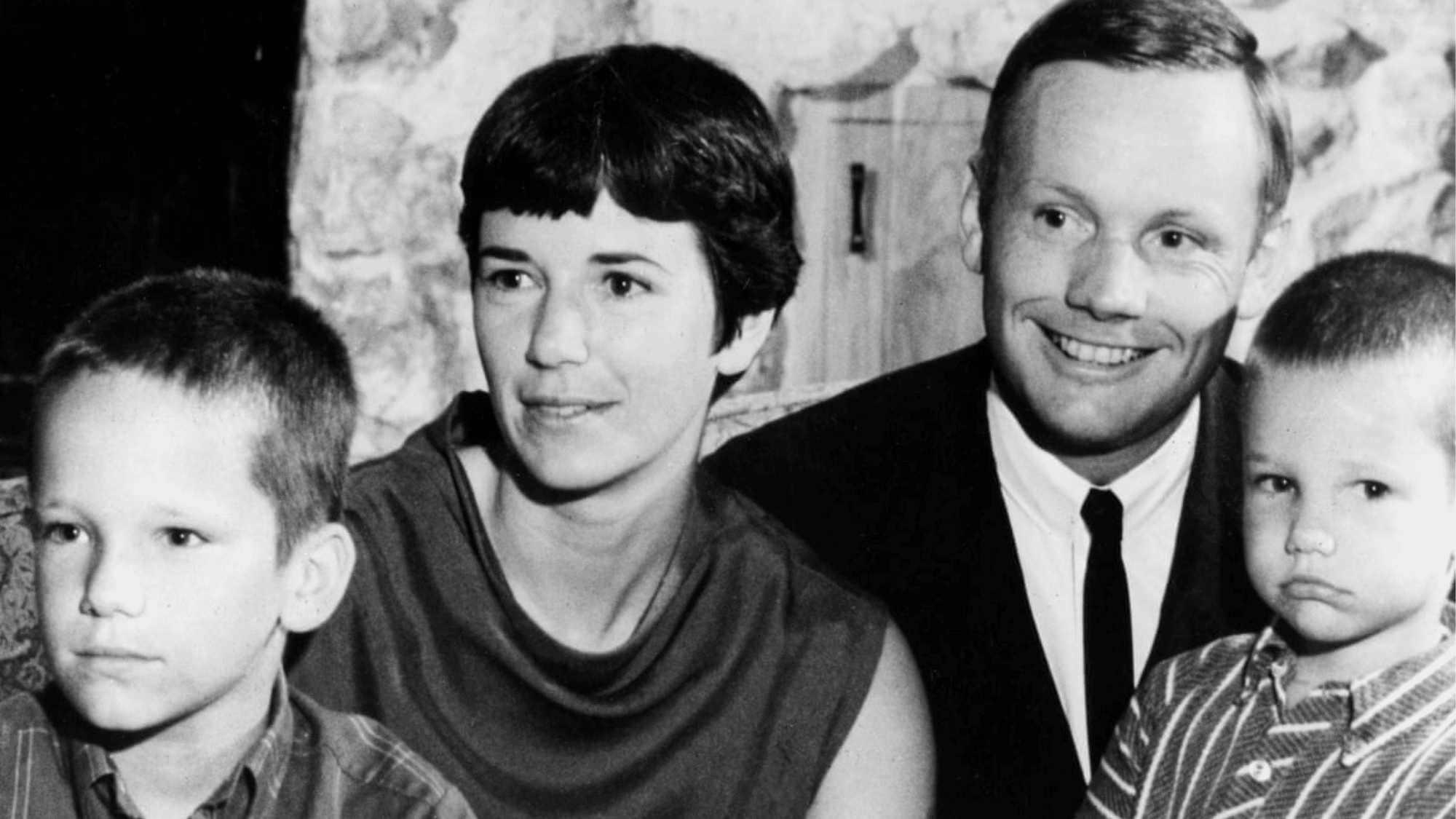 Black and white portrait of Neil Armstrong smiling beside his wife Janet Armstrong and two young sons.