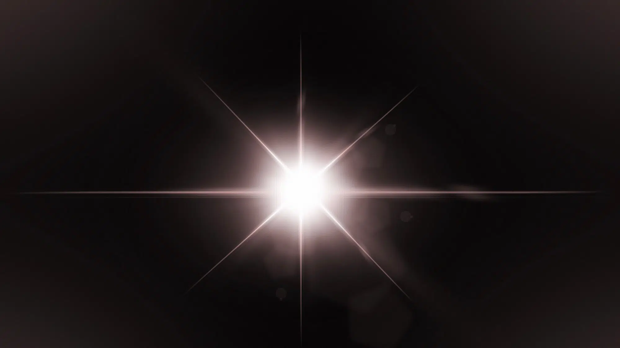 Bright white starburst lens flare centered against a dark background with radiating light streaks.