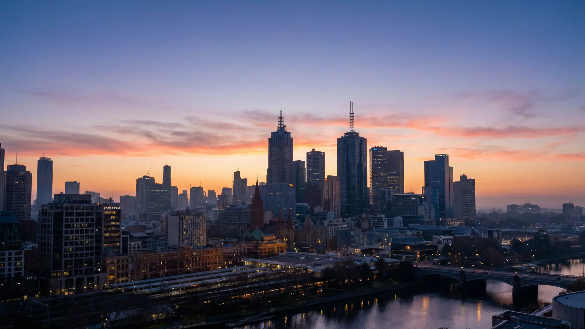 City skyline during civil twilight, warm orange and pink glow near horizon, buildings clearly visible, soft natural lighting