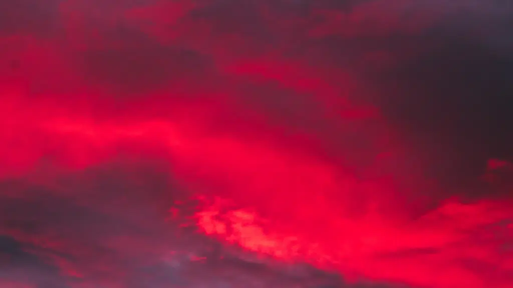 Vivid, saturated red clouds dominate a dark, dramatic sunset or twilight sky