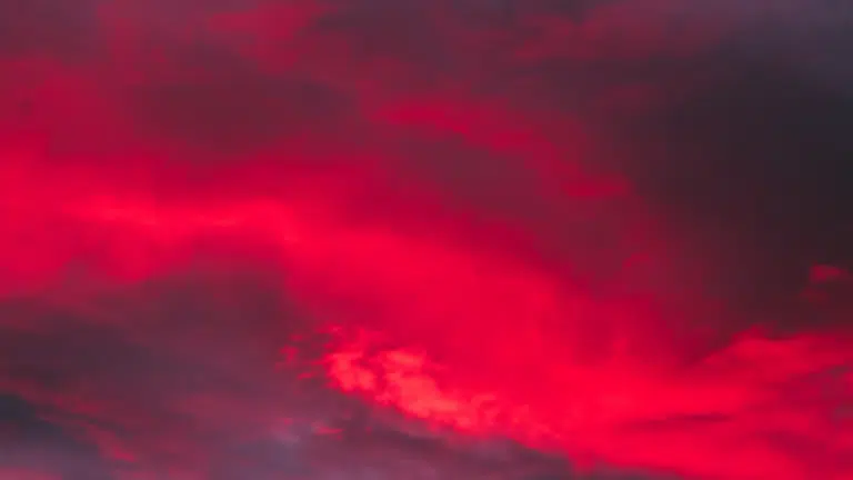 Vivid, saturated red clouds dominate a dark, dramatic sunset or twilight sky