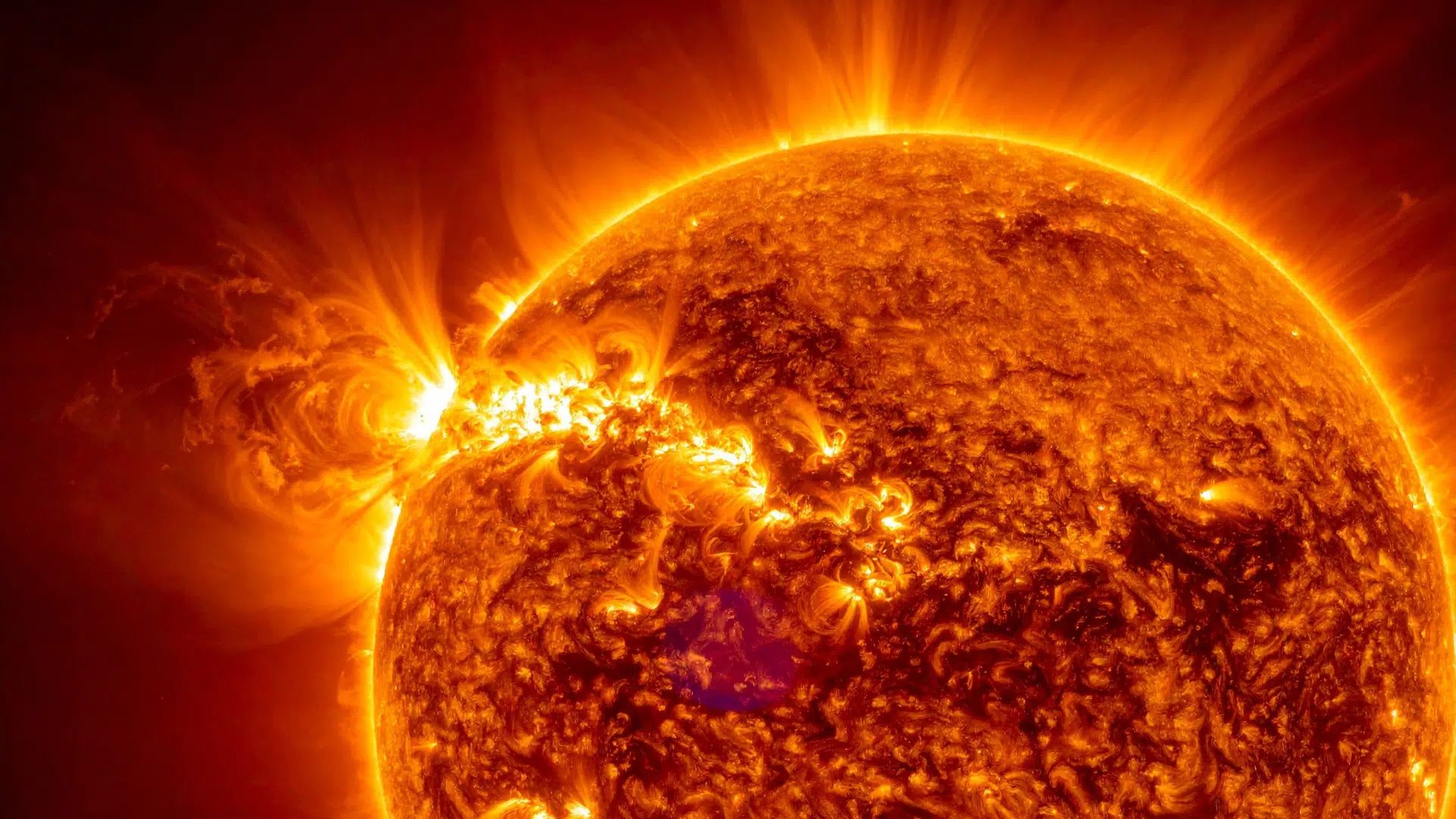 close-up of the Sun's surface showing intense solar activity, including a prominent solar flare erupting from the limb