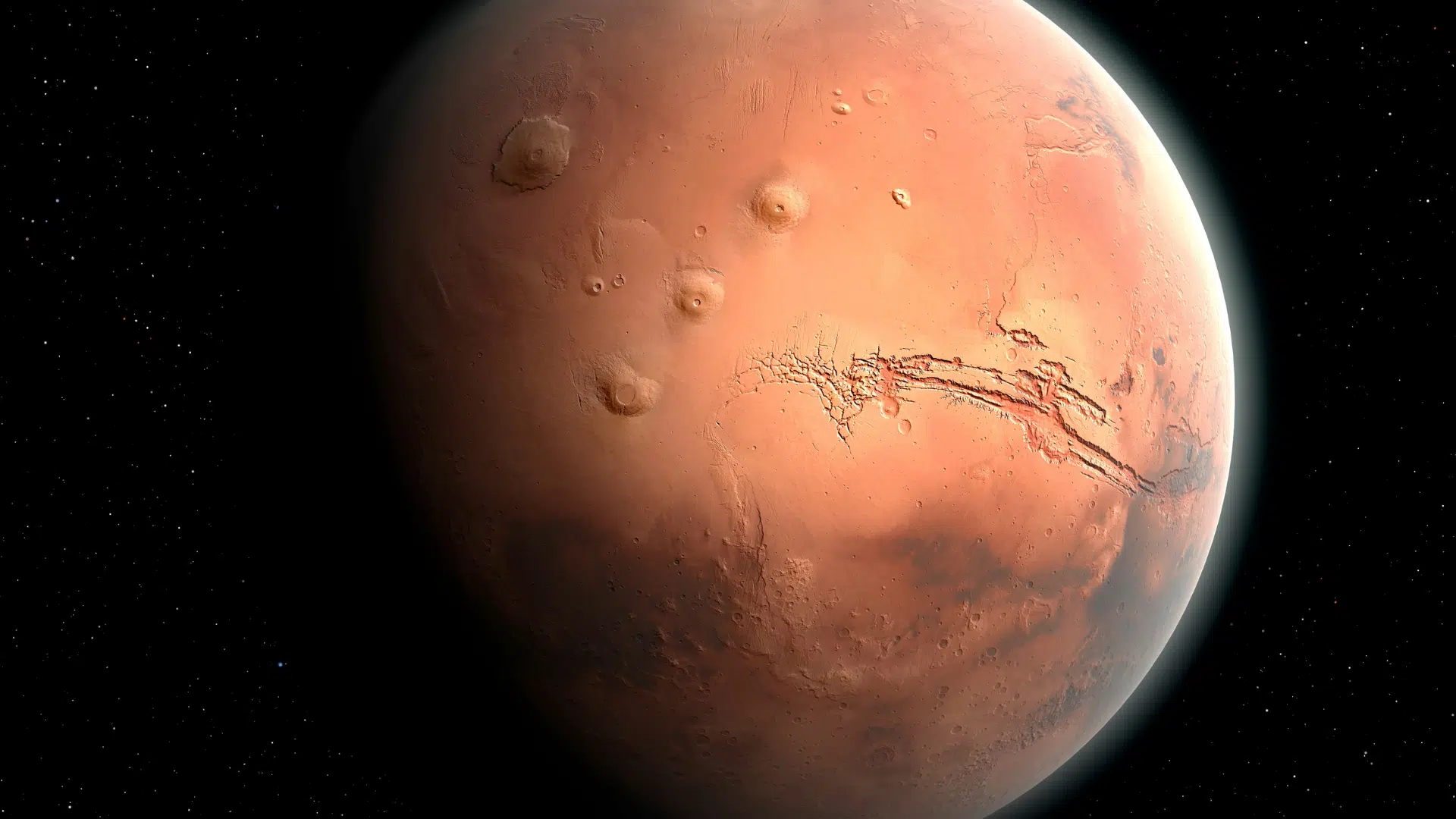 the reddish-orange surface of Mars showing impact craters and deep canyons set against the blackness of space dotted with stars