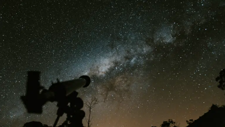 A telescope under a starry night sky to observe planets and stars