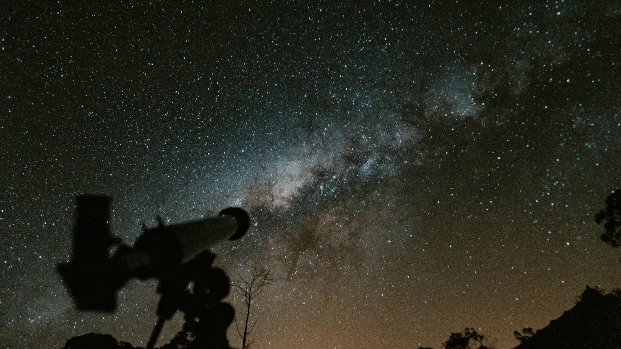 A telescope under a starry night sky to observe planets and stars