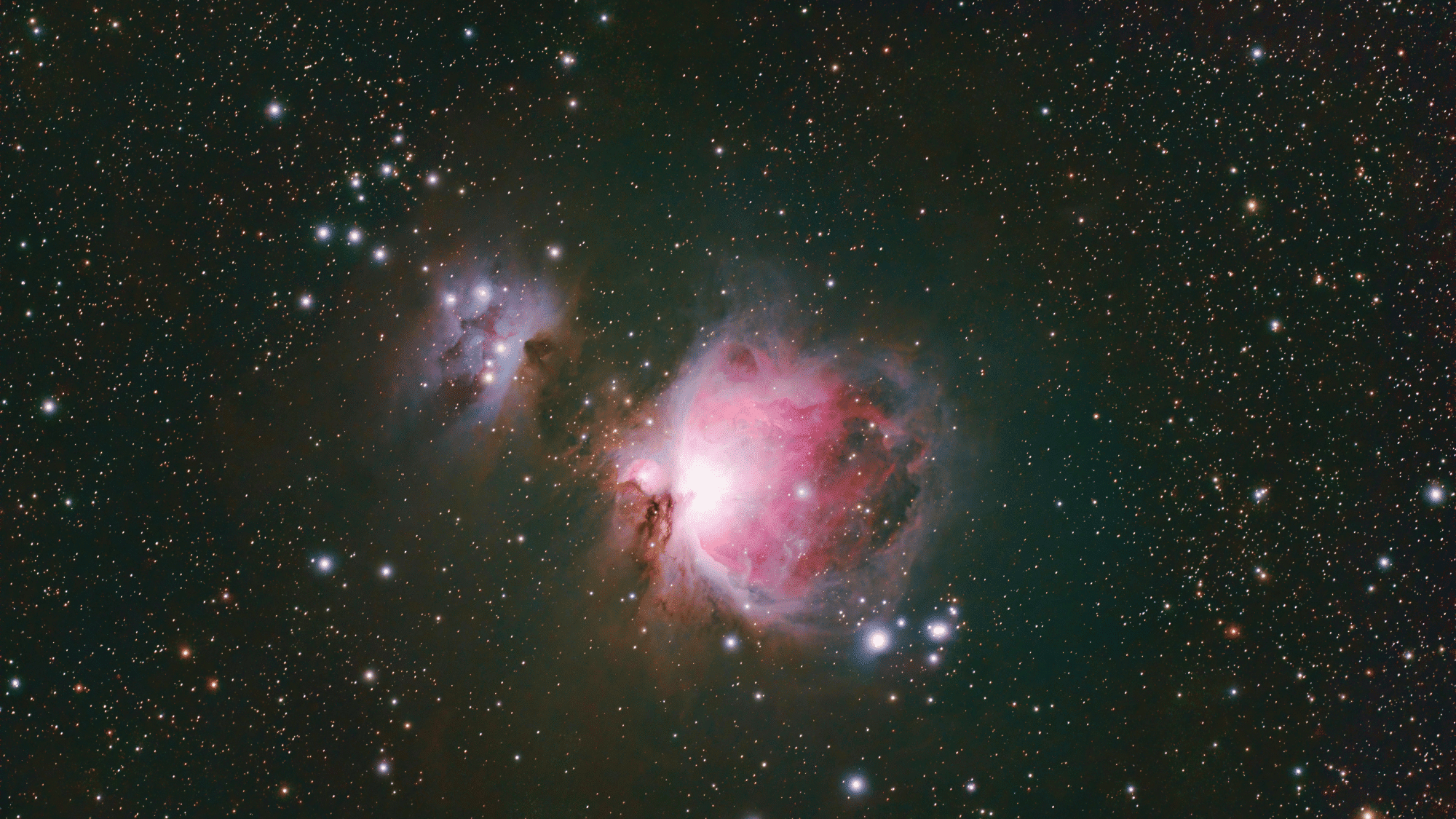 Astrophotograph capturing the bright pink and red hues of the Orion Nebula (M42) alongside the smaller Running Man Nebula (NGC 1977).