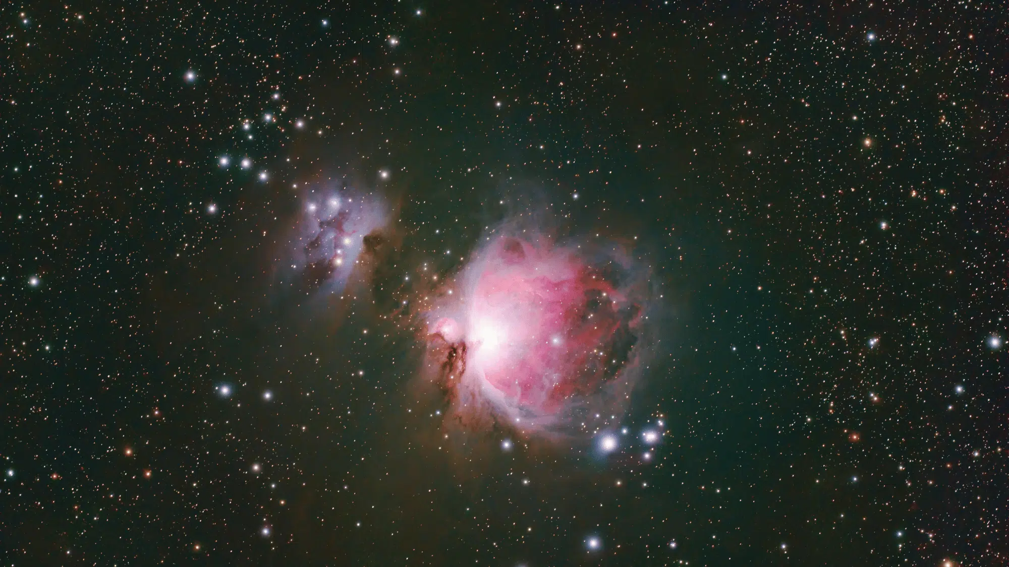 Astrophotograph capturing the bright pink and red hues of the Orion Nebula (M42) alongside the smaller Running Man Nebula (NGC 1977).