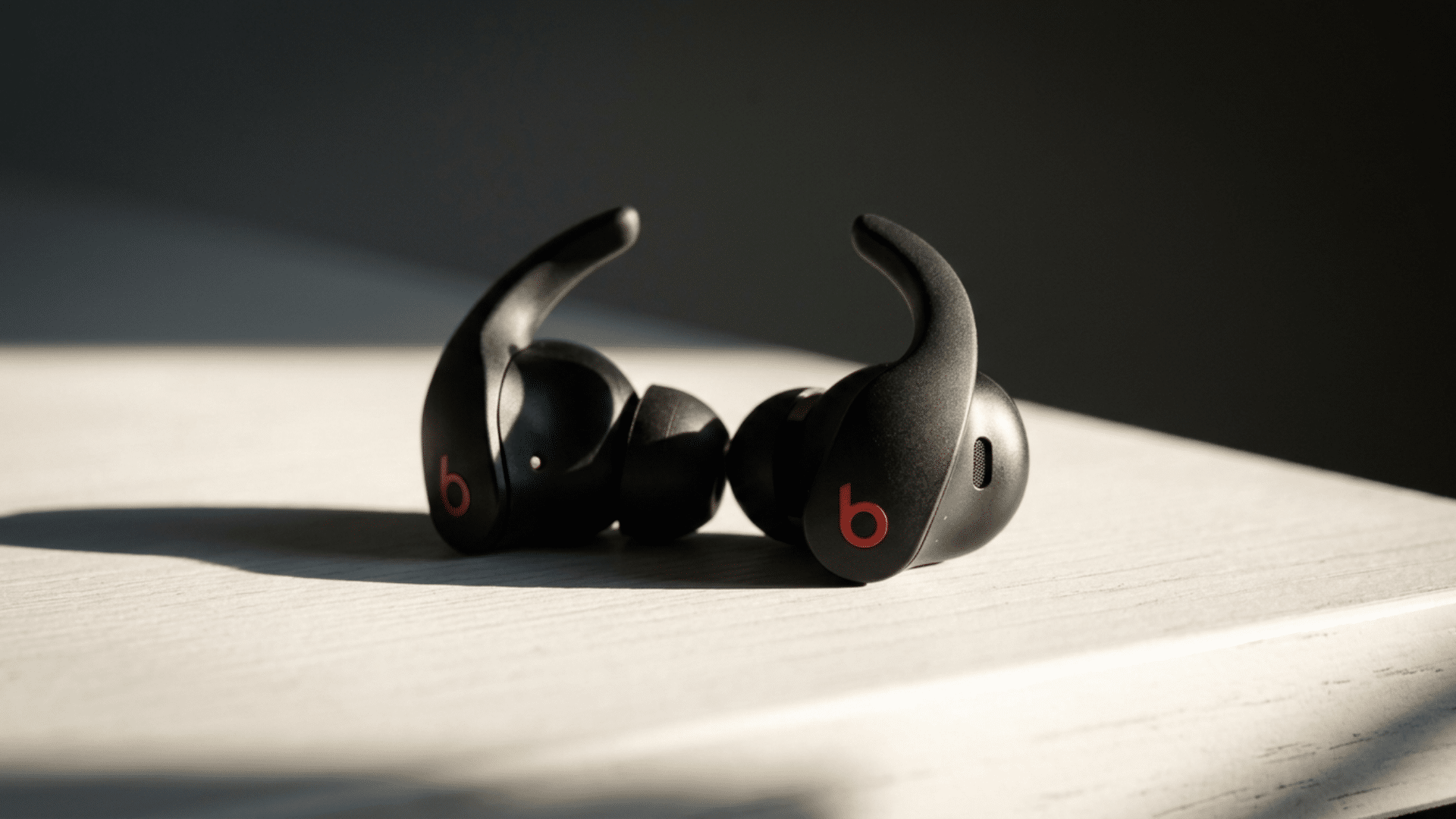 Beats Fit Pro earbuds displayed on a clean desk with soft lighting in a minimal setup