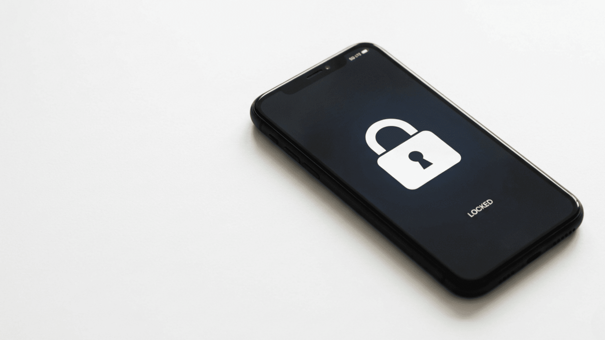 Smartphone lying on a surface showing a locked screen with a padlock icon.