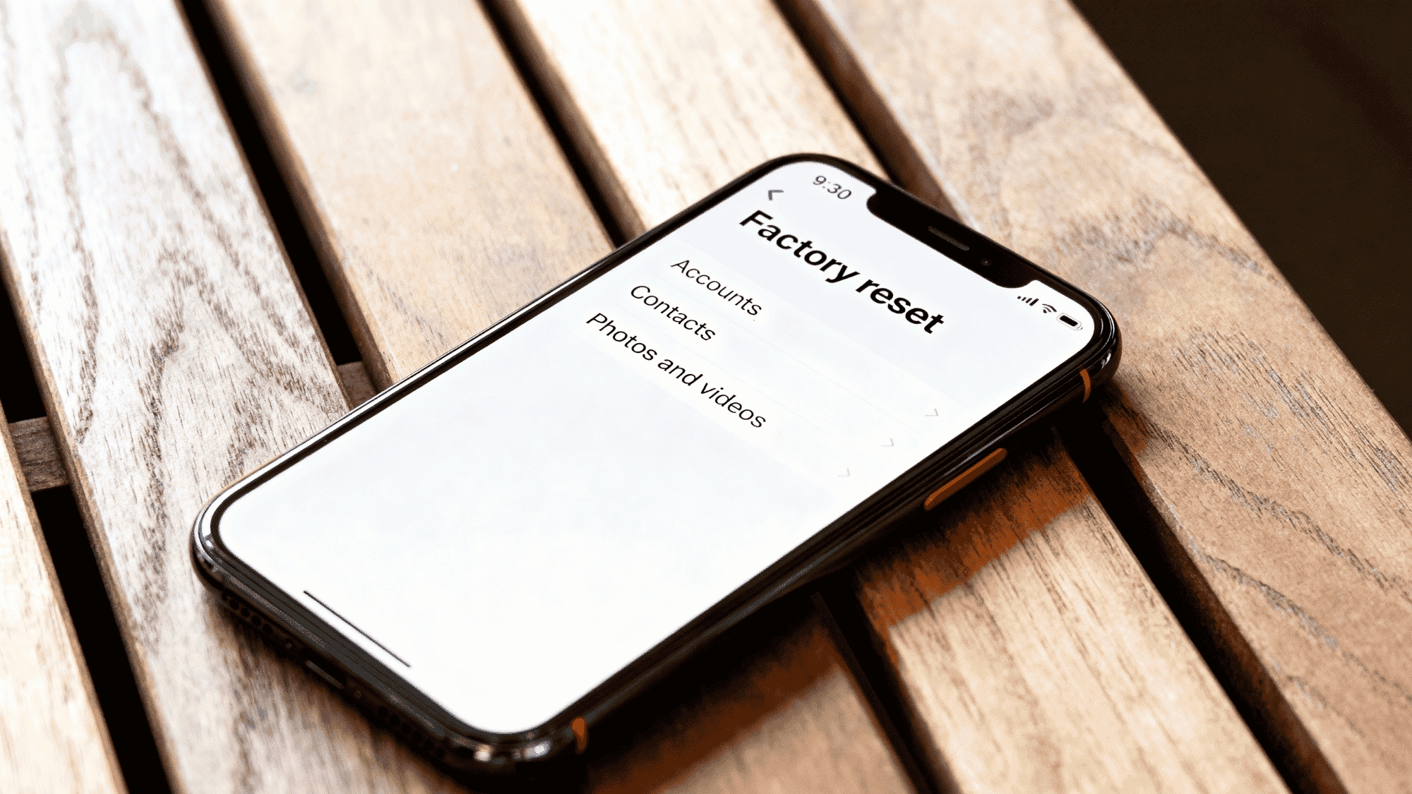 _Smartphone showing factory reset option on screen placed on a wooden table