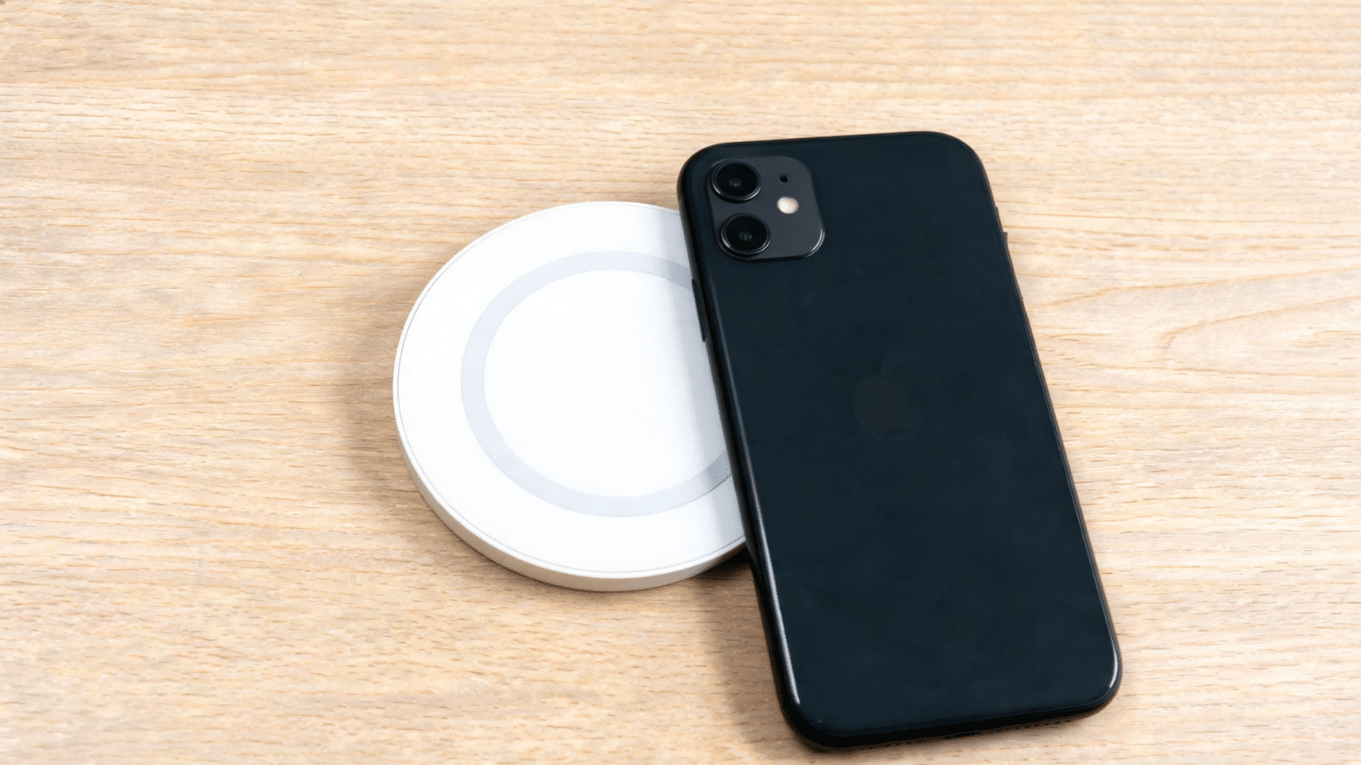 iPhone 11 placed on a MagSafe charger without magnetic alignment on a clean desk surface