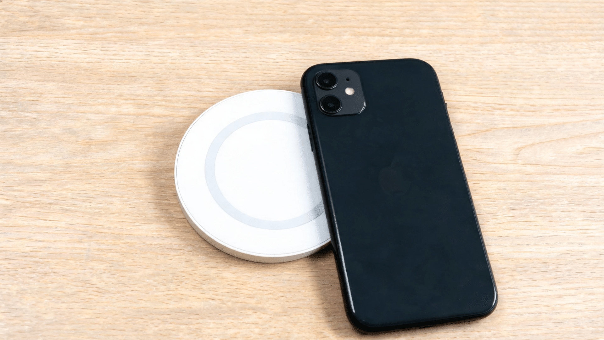 iPhone 11 placed on a MagSafe charger without magnetic alignment on a clean desk surface