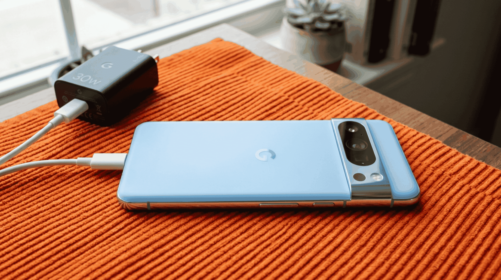 Google Pixel 8 Pro charging with 30W wired charger on a nightstand with charging indicator on screen