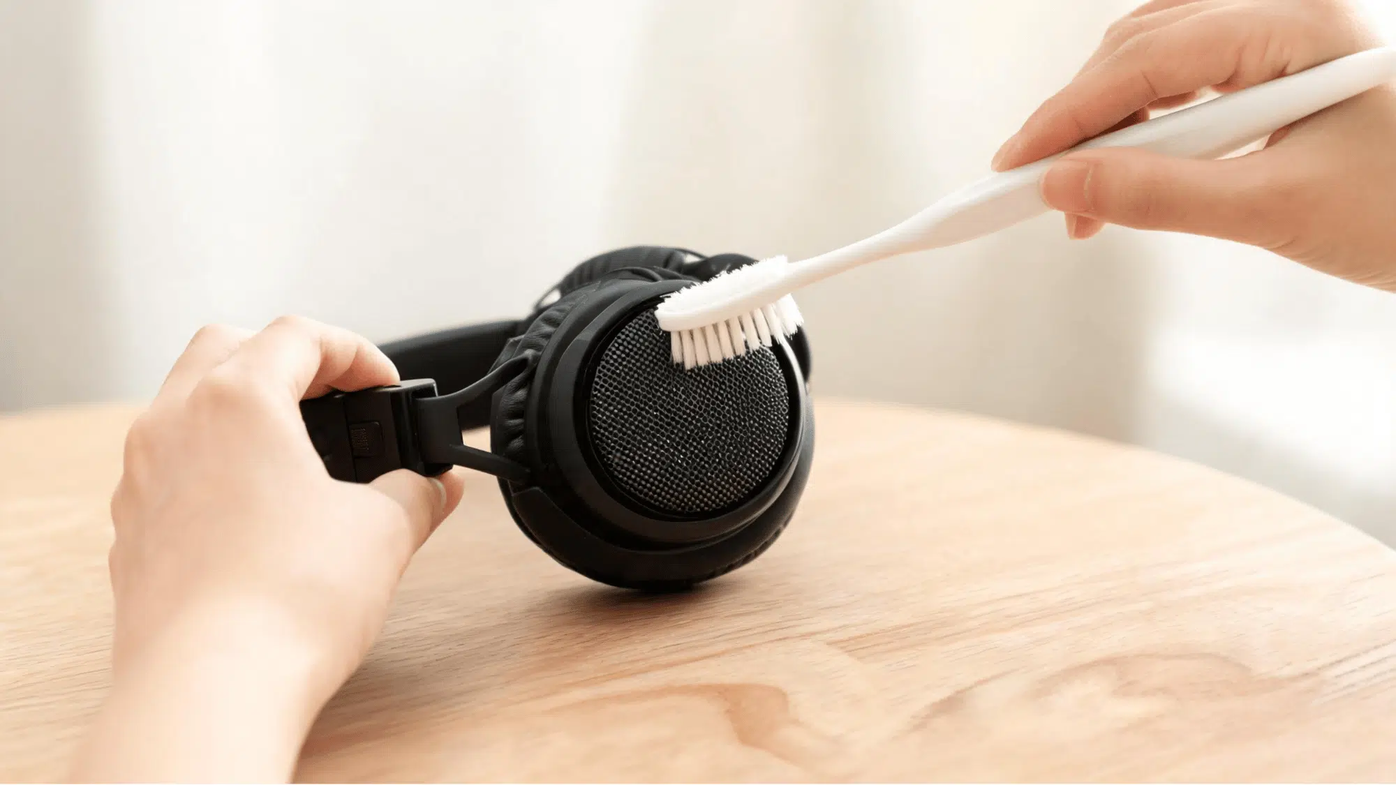 Soft brush cleaning black speaker mesh grille on over-ear headphones