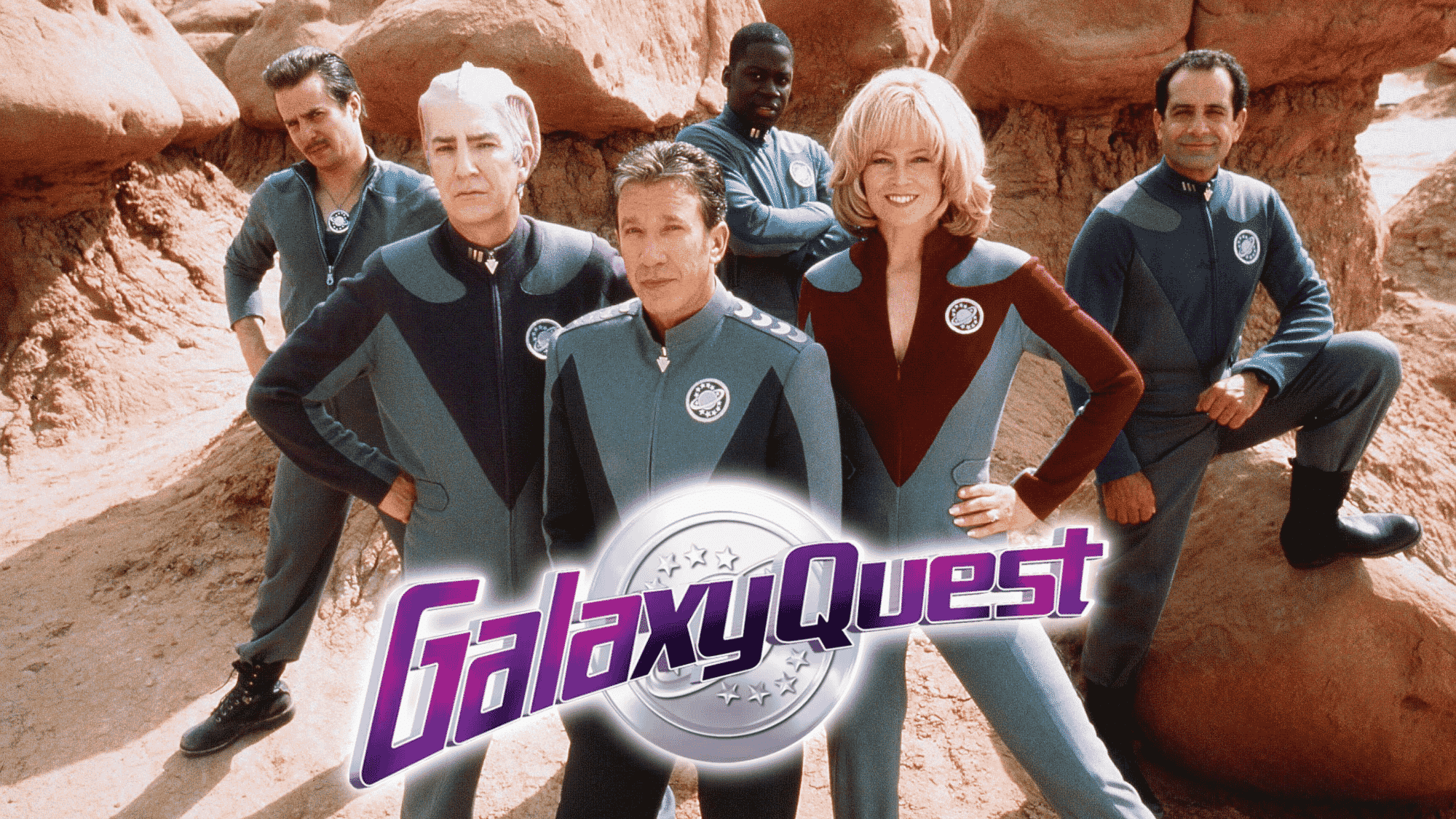 Galaxy Quest cast posing in sci-fi uniforms on alien planet.