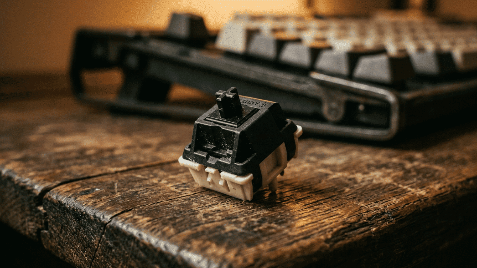 Cherry MX Black switch with dark housing resting on rustic wooden desk surface