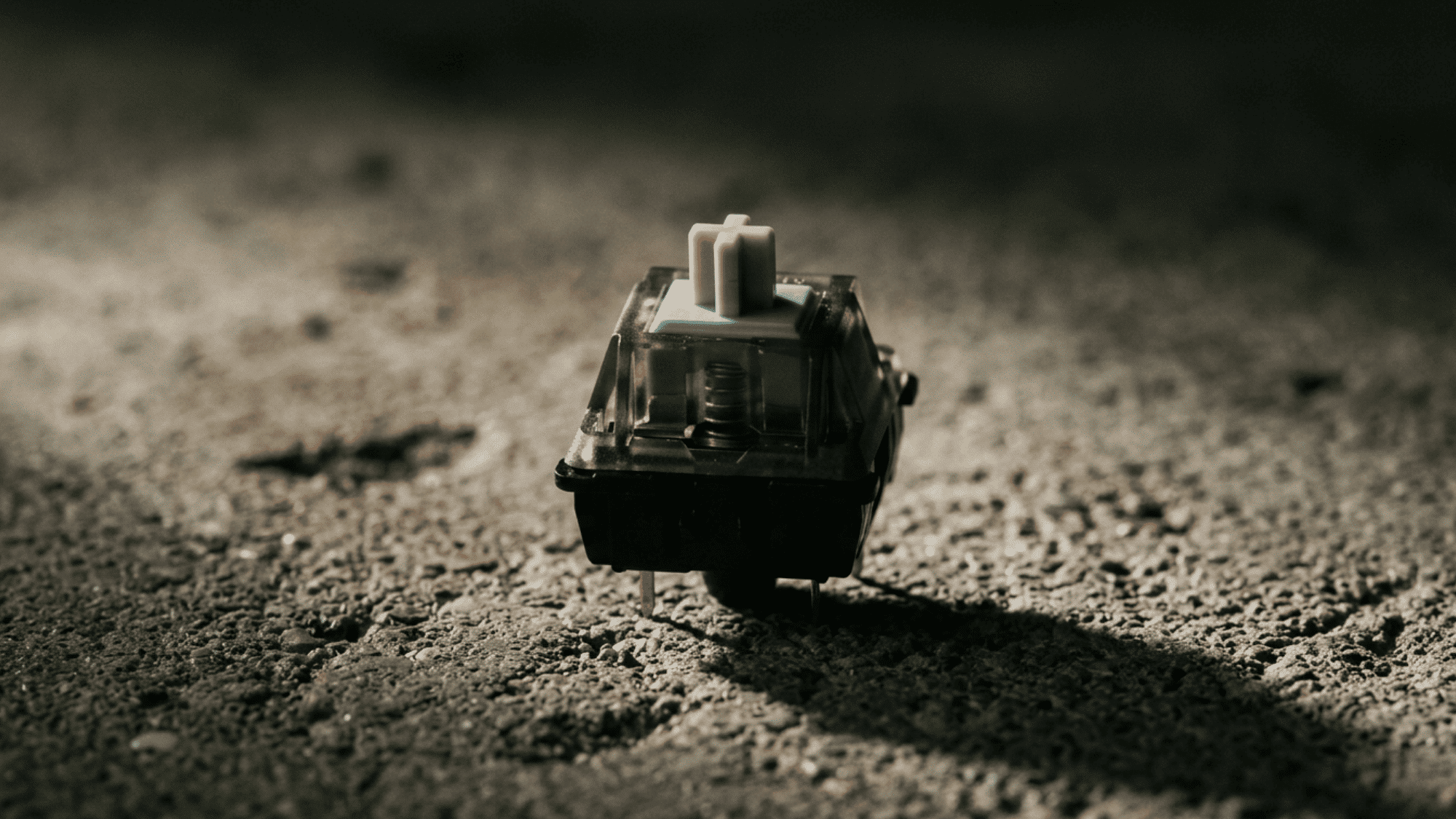 Durock T1 switch with smoke-tinted housing and long-pole stem on dark asphalt surface