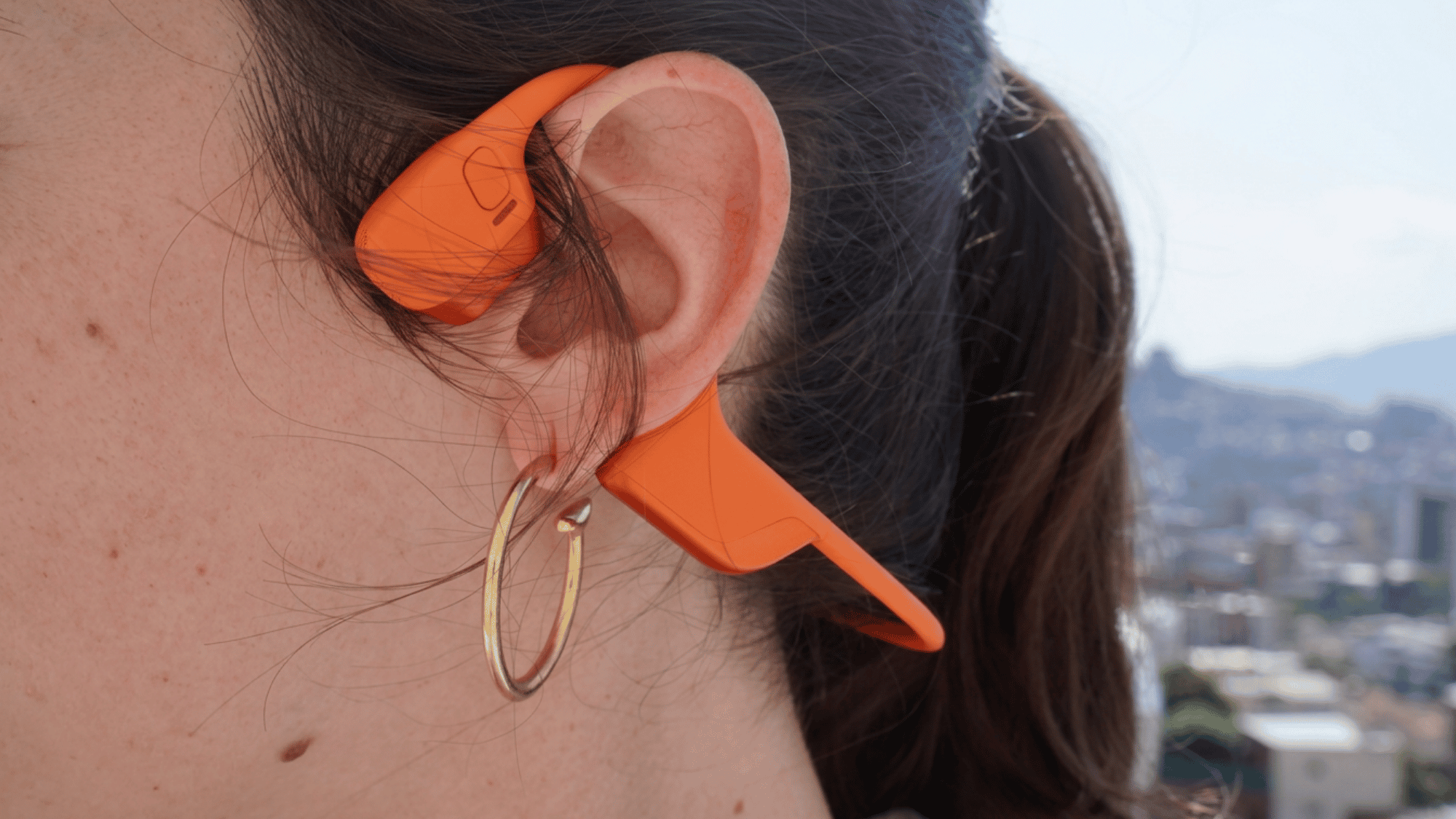 A person wearing bone conduction headphones resting on their cheekbone.