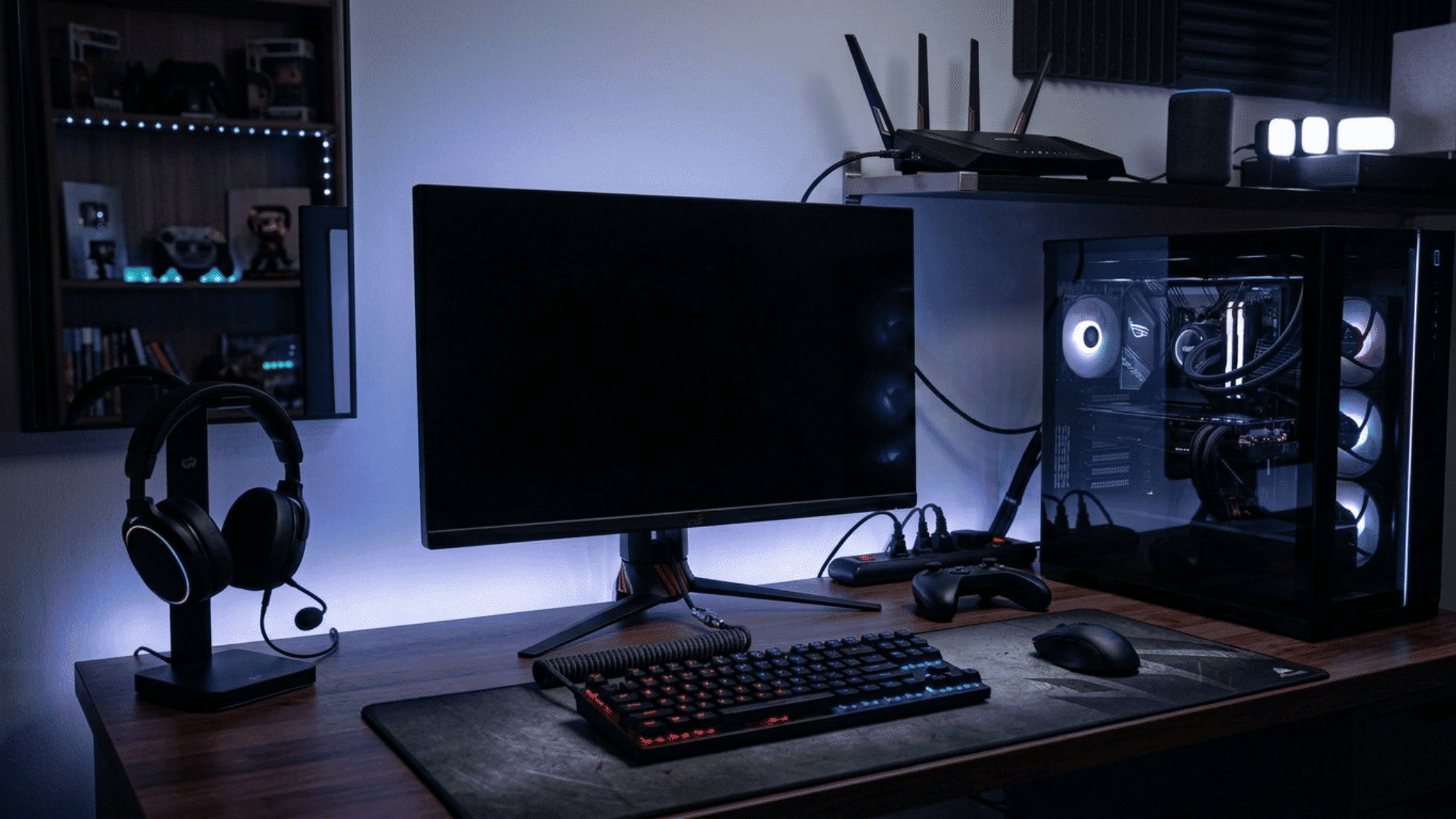 Gaming desk with PC tower, monitor, mechanical keyboard, headset, and router