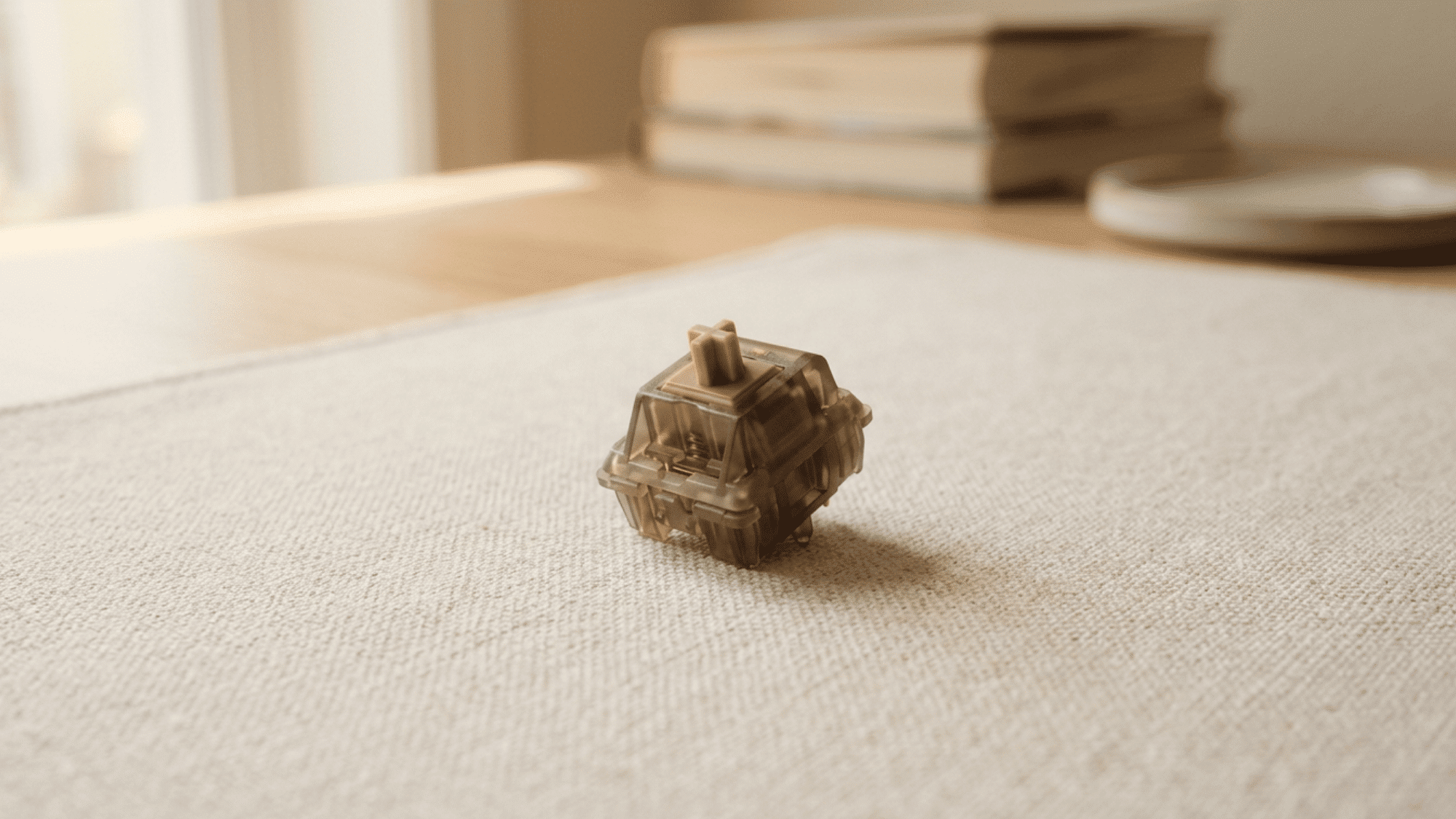 JWK Alpaca switch with smoky brown translucent housing on beige fabric desk mat