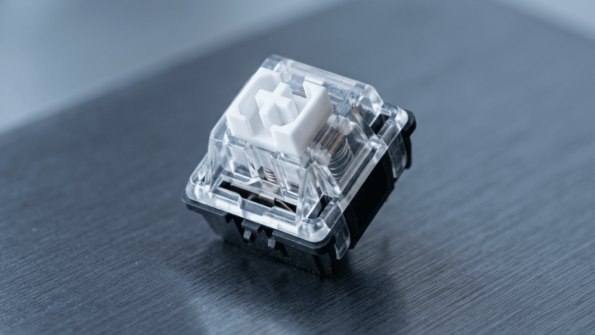 Kailh Box White switch with clear housing and boxed white stem on dark wood desk