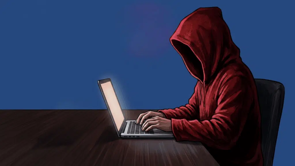 A red hooded figure sits at a desk, typing on a laptop.
