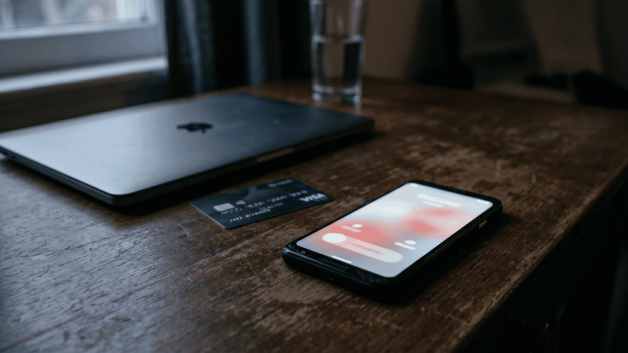 Phone with blurred scam call beside laptop and bank card