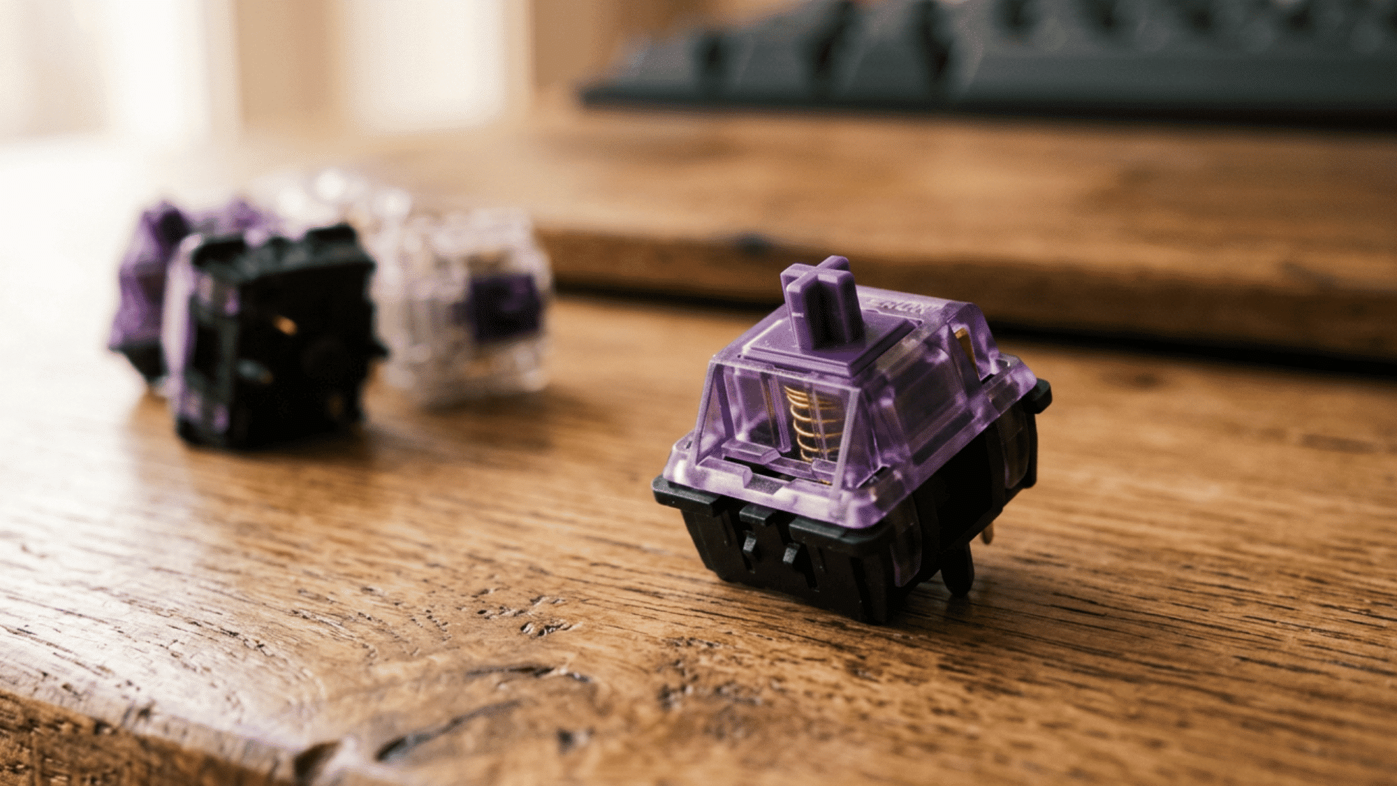 Zealios V2 switch with purple translucent housing and gold spring on wooden desk