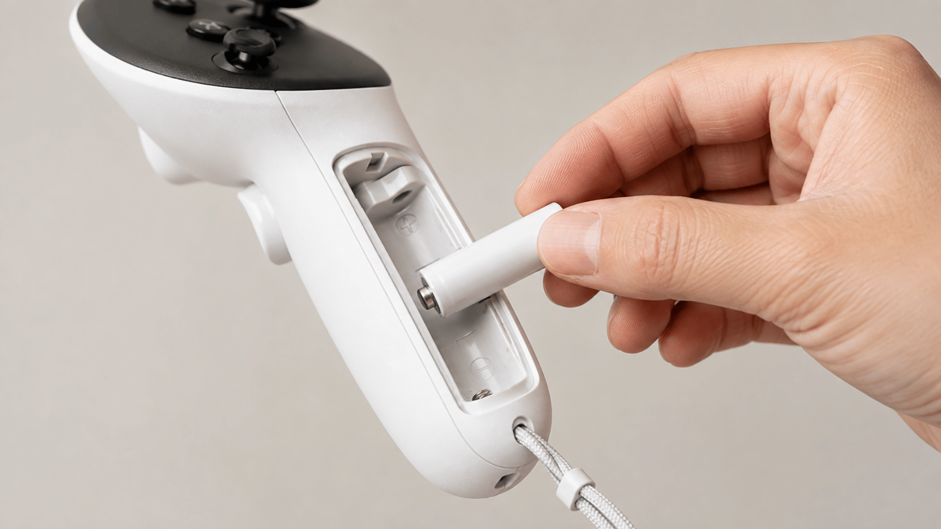 hand inserting a rechargeable AA battery into a Meta Quest 3 controller