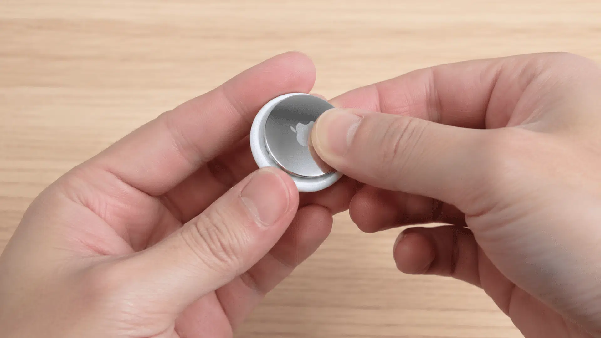 hands opening airtag cover to access the replaceable cr2032 battery inside