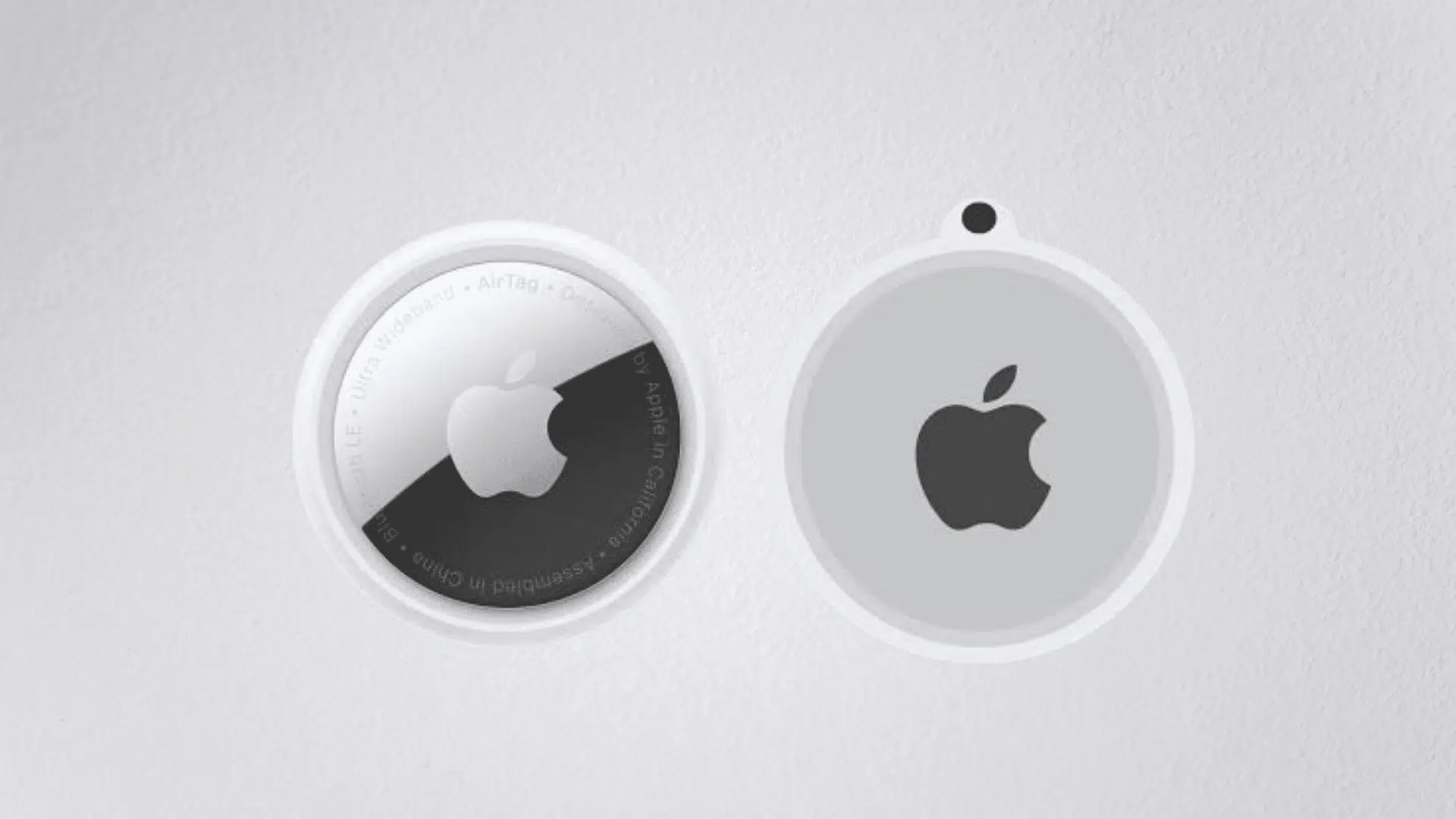 two airtags showing the front and back design with apple logo on a white surface